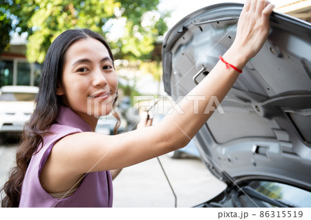 Asian trying to fix her broken vehicle. Asian trying to fix her broken vehicle. 86315519