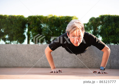 Active Asian young man making an outdoor body weight exercise close up, sportsman doing body weight workout by pushup and plank. Asian sportsman exercising for muscle and body building. Active Asian young man making an outdoor body weight exercise close up, sportsman doing body weight workout by pushup and plank. Asian sportsman exercising for muscle and body building. 86323777