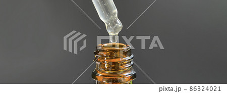 Pipette with a drop of face serum or oil for the face and hyaluronic acid on beautiful black background, close-up. 86324021