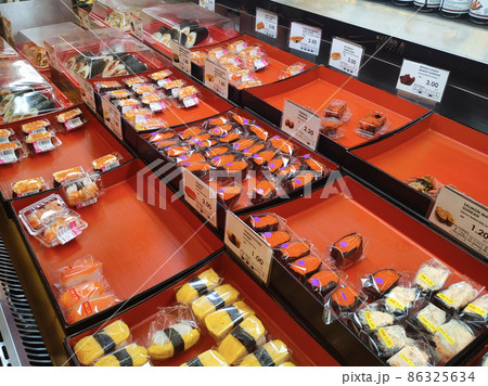 SEREMBAN, MALAYSIA - JANUARY 29, 2022: Selected focused on sushi being displayed for sale in a chiller. Separated in the tray according to type and placed a price tag for the convenience of customers. SEREMBAN, MALAYSIA - JANUARY 29, 2022: Selected focused on sushi being displayed for sale in a chiller. Separated in the tray according to type and placed a price tag for the convenience of customers. 86325634