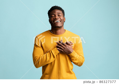 Religious young black man praying on blue Religious young black man praying on blue 86327377