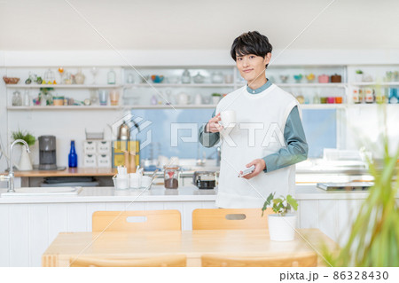 自宅のキッチンでコーヒーを飲む若い男性 86328430