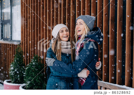 Adult female friends embracing and laughing rejoicing at the meet and snowy cold weather. Adult female friends embracing and laughing rejoicing at the meet and snowy cold weather. 86328692