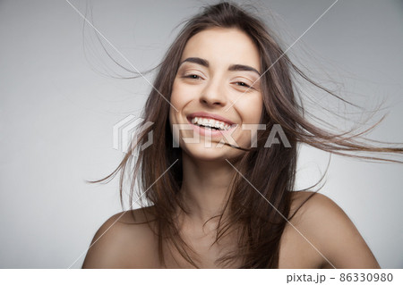 Attractive smiling woman with long hair on grey 86330980