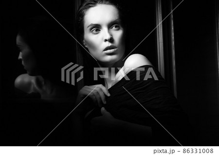 Beautiful young woman near a glass in interior 86331008