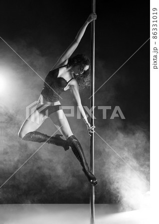 Young slim pole dance woman exercising over dark Young slim pole dance woman exercising over dark 86331019