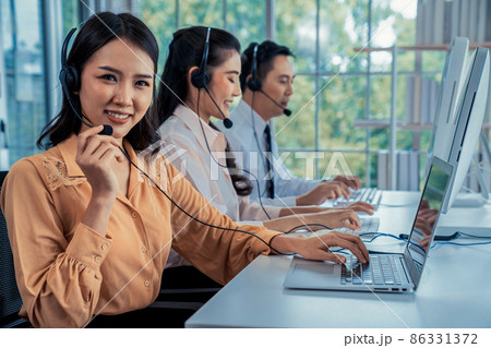 Business people wearing headset working actively in office Business people wearing headset working actively in office 86331372
