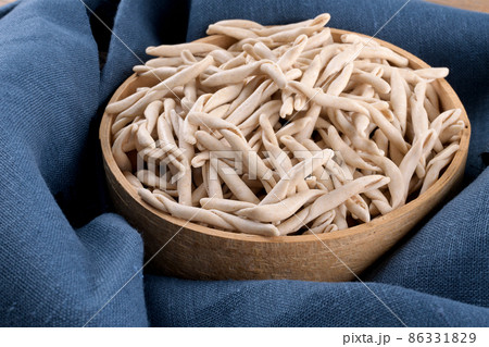 Whole grain wheat apulian pasta maccaruni in a sieve on blue linen napkin. Italian homemade pasta background 86331829