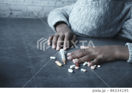 drug addiction concept with hand holding pills and syringe laying on floor drug addiction concept with hand holding pills and syringe laying on floor 86334195