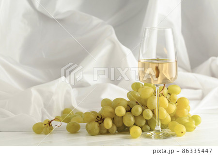 Glass of white wine and grape cluster. 86335447