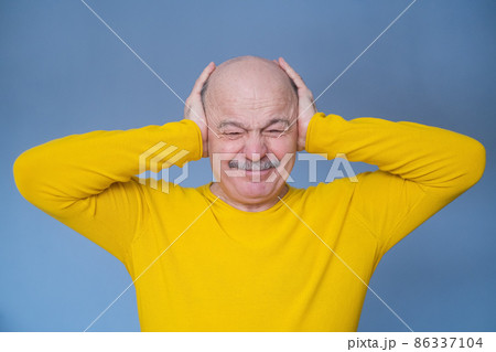 Senior man covering his ears with raised palms having terrible headache. Senior man covering his ears with raised palms having terrible headache. 86337104