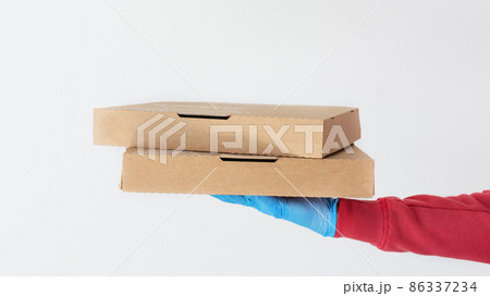 Courier hand in protective glove holding cardboard pizza boxes over white background. 86337234