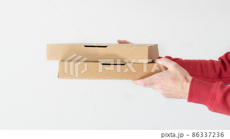 Courier hands holding cardboard pizza boxes over white background. Courier hands holding cardboard pizza boxes over white background. 86337236