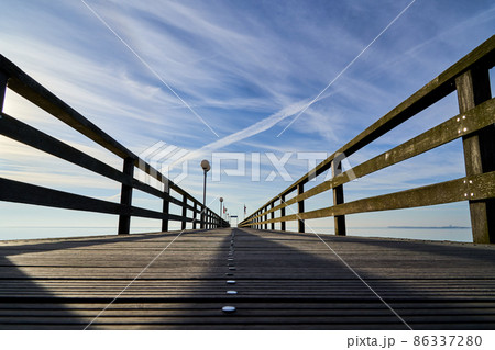 Ground view over an empty wooden pier with nails and a railing, central perspective with decreasing depth of field Ground view over an empty wooden pier with nails and a railing, central perspective with decreasing depth of field 86337280