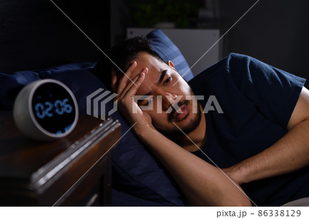Depressed young Asian man lying in bed cannot sleep from insomnia. focus on clock Depressed young Asian man lying in bed cannot sleep from insomnia. focus on clock 86338129