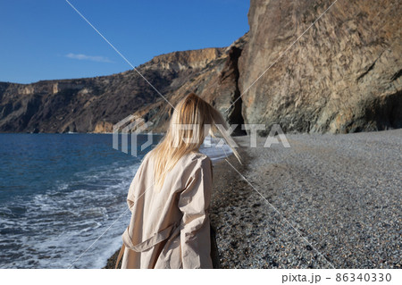 a young beautiful woman runs along a pebble beach against the backdrop of sea 86340330