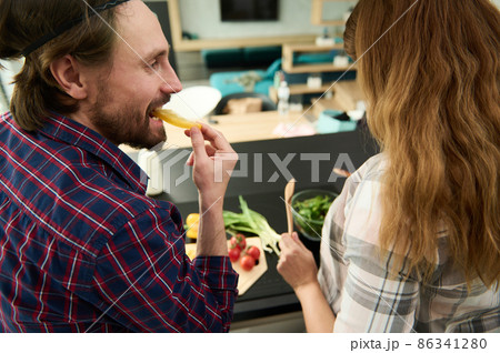 Rear view of a handsome Caucasian loving heterosexual couple preparing healthy meal together in the kitchen island Rear view of a handsome Caucasian loving heterosexual couple preparing healthy meal together in the kitchen island 86341280