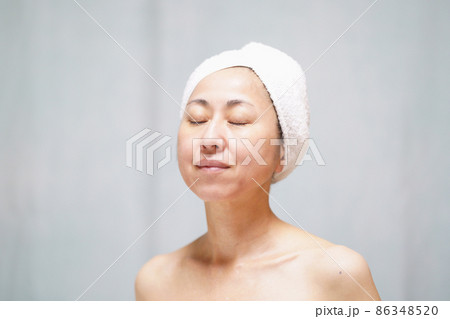 頭にタオルを巻いて目を閉じる素顔の中年女性　 86348520