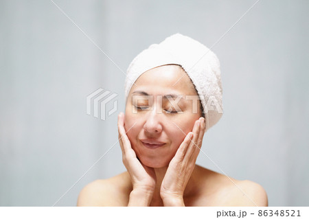 頭にタオルを巻いて頬を両手で包む素顔の中年女性　 86348521