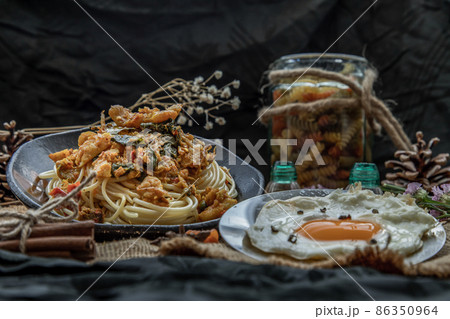 Spaghetti topped with Stir fried spicy snapper on a brown plate Served with Fried Egg. Spaghetti topped with Stir fried spicy snapper on a brown plate Served with Fried Egg. 86350964