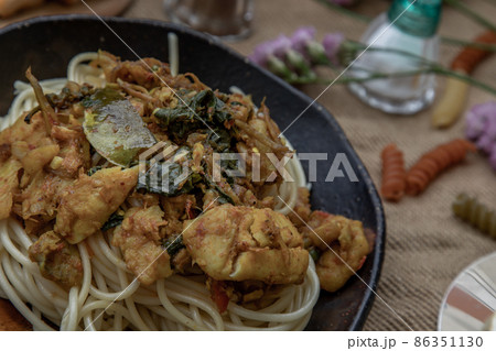 Close-up of Spaghetti topped with Stir fried spicy snapper on a brown plate. 86351130