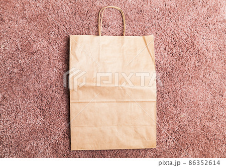 An empty paper bag lays on pink a  carpet 86352614
