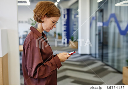 Tattooed Woman using Smartphone in Office Tattooed Woman using Smartphone in Office 86354185