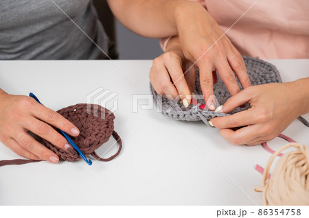 A woman teaches her friend needlework. Two women are crocheting a basket of cotton yarn. A woman teaches her friend needlework. Two women are crocheting a basket of cotton yarn. 86354758