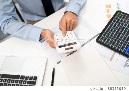 Working Man Conept The male officer sitting at his desk, holding the calculator, and pressing it 86355039