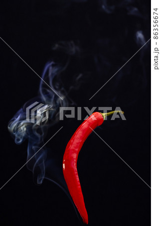 Red hot chili peppers against a black background with smoke coming from it, depicting it to be Red hot chili peppers against a black background with smoke coming from it, depicting it to be 86356674