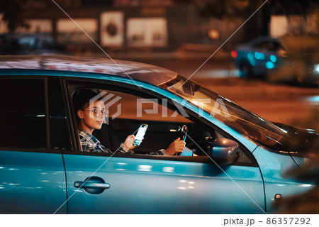 Lost female driver using mobile phone while driving at night. 86357292