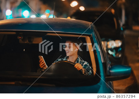 Lost female driver using mobile phone while driving at night. Lost female driver using mobile phone while driving at night. 86357294