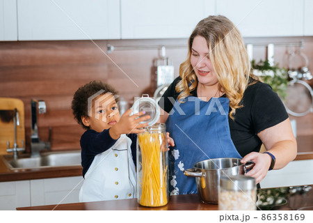 Mom and daughter cook spaghetti in the kitchen Mom and daughter cook spaghetti in the kitchen 86358169
