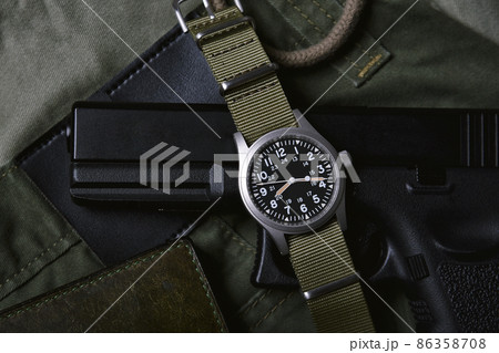 Vintage military watch wallet and pistol on army green background, Classic timepiece wristwatch Vintage military watch wallet and pistol on army green background, Classic timepiece wristwatch 86358708