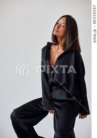 Young slim woman model in sunglasses, black military uniform stands with her legs wide apart and arms crossed at chest. 86359567