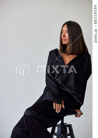Young slim woman model in sunglasses, black military uniform stands with her legs wide apart and arms crossed at chest. Young slim woman model in sunglasses, black military uniform stands with her legs wide apart and arms crossed at chest. 86359584