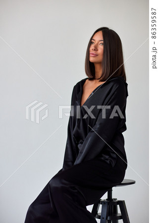 Young slim woman model in sunglasses, black military uniform stands with her legs wide apart and arms crossed at chest. Young slim woman model in sunglasses, black military uniform stands with her legs wide apart and arms crossed at chest. 86359587