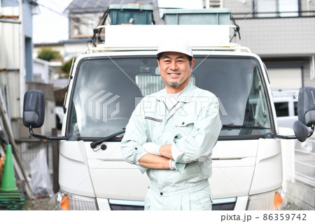 トラックの前で腕組みをする作業服を着たミドル男性 86359742