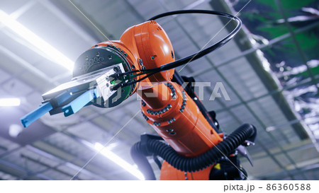 Industrial robot arm manipulating the assembly at the modern factory. Low angle shot Industrial robot arm manipulating the assembly at the modern factory. Low angle shot 86360588