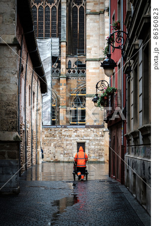 municipal worker with raincoat collecting garbage with his cart, city Leon spain 86360823