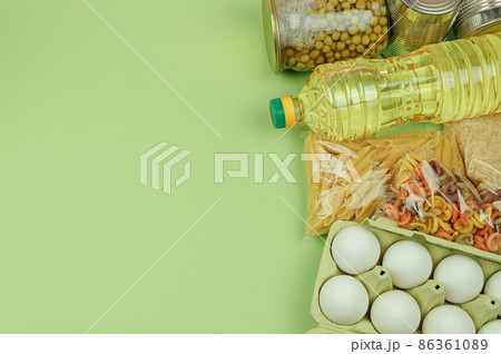 Donation food green background with copy space. Flat lay. Top view, mock up. Rice, canned food, butter, eggs, pasta. Food donation or food delivery concept. Online shopping during quarantine. Donation food green background with copy space. Flat lay. Top view, mock up. Rice, canned food, butter, eggs, pasta. Food donation or food delivery concept. Online shopping during quarantine. 86361089