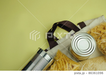 Food donations in a linen bag. Food delivery in an eco bag, canned food, pasta. Eco bag with food supplies. View from above. The concept of donation and mercy. Copy space 86361096
