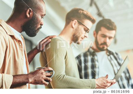 Three male coworkers being concentrated on laptop screen Three male coworkers being concentrated on laptop screen 86361696