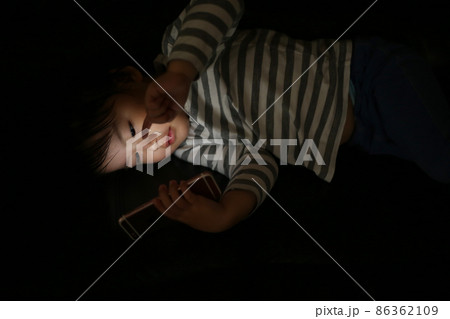 暗い中でスマートフォンを使う男の子 86362109