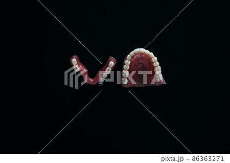 Full removable plastic denture of the jaws. A set of dentures on a black background. Two acrylic dentures. Upper and lower jaws with fake teeth. Dentures or false teeth, close-up. Copy space Full removable plastic denture of the jaws. A set of dentures on a black background. Two acrylic dentures. Upper and lower jaws with fake teeth. Dentures or false teeth, close-up. Copy space 86363271