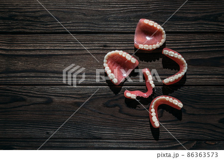 Dentures on a dark background. Close-up of dentures. Full removable plastic denture of the jaws. Prosthetic dentistry. False teeth. Close-up of plastic dentures. Teeth on a black background 86363573