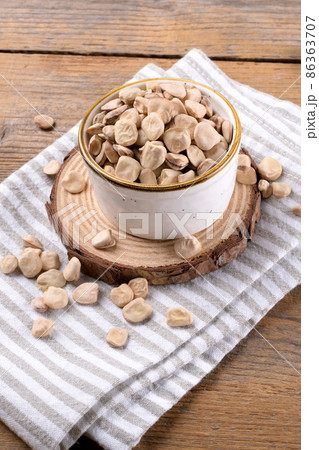 Dry raw cicerchia or indian pea on a ceramic bowl with napkin on wooden background, close up 86363707