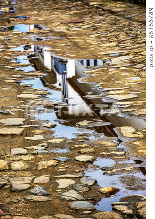 Reflections of an old colonial style house in a puddle on Paraty city street 86366789