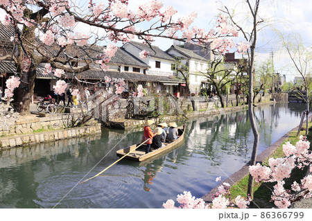 People in old-fashioned boat and sakura flowers, Kurashiki canal in Bikan district, Kurashiki city, Japan 86366799