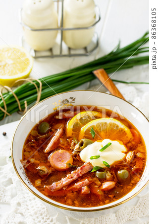 Traditional Russian soup Solyanka with meat, sausages, vegetables, capers, pickles and olives with lemon on wooden table. Rustic style. Traditional Russian soup Solyanka with meat, sausages, vegetables, capers, pickles and olives with lemon on wooden table. Rustic style. 86368105